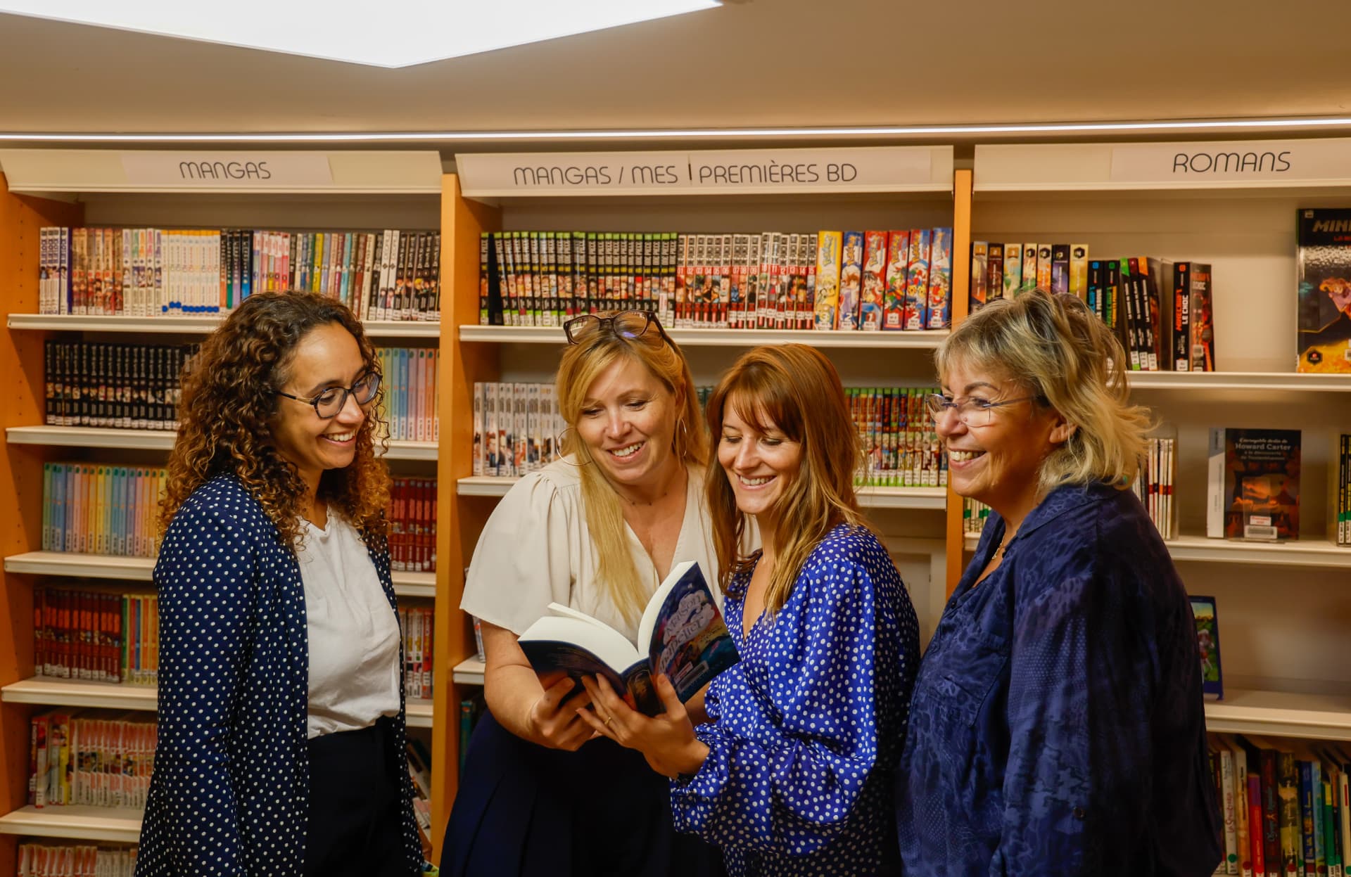 Équipe souriante d'une librairie au milieu des rayonnages