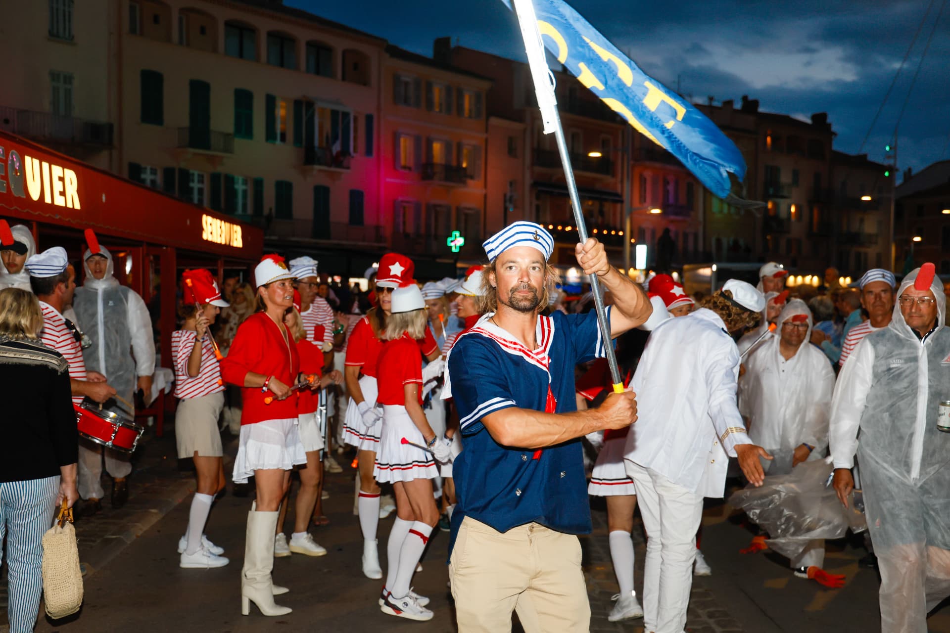 Défilé nocturne costumé, un marin portant un drapeau bleu au premier plan